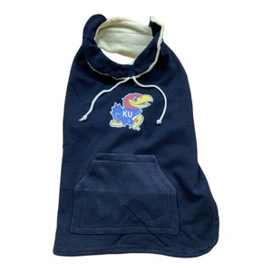 May include: A navy blue hooded dog sweater with a white fleece lining. The sweater features a KU logo with a blue bird mascot. The sweater has a front pocket.