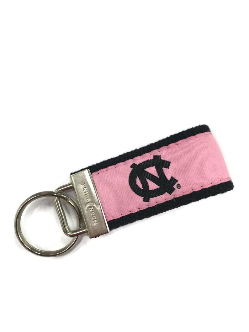 May include: Pink and black key chain with a black embroidered "N" logo and the text "Moonshine" on the metal ring.