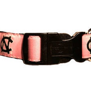 May include: Pink dog collar with a black buckle and a white UNC logo on each side.