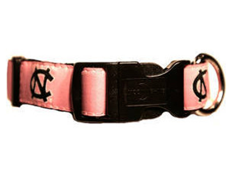 May include: Pink dog collar with a black buckle and a white UNC logo on each side.