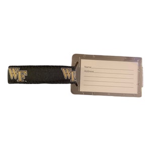 May include: A black luggage tag with a gold "WF" logo and a clear plastic window with spaces for a name and address.