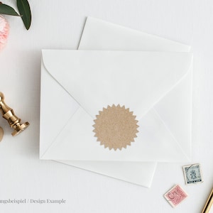 May include: A white envelope with a brown paper seal and a gold pen on a white surface. The envelope is sealed with a gold wax seal. There are two stamps on the envelope. The text on the envelope reads "Gestaltungsbeispiel / Design Example".