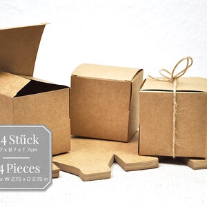 K&ouml;nnte beinhalten: Ein Set mit 24 braunen Geschenkkartons mit Deckel. Die Kartons sind 7 cm breit, 7 cm lang und 7 cm tief. Ein Karton ist offen und der andere ist mit Schnur gebunden.