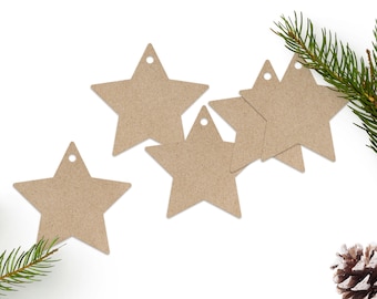 May include: Kraft paper star-shaped gift tags with a small hole at the top for stringing. The tags are arranged on a white background with green pine needles and a pine cone, suggesting a holiday or seasonal theme.