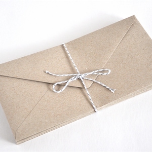 May include: A stack of brown paper envelopes tied together with a white and gray twine bow.