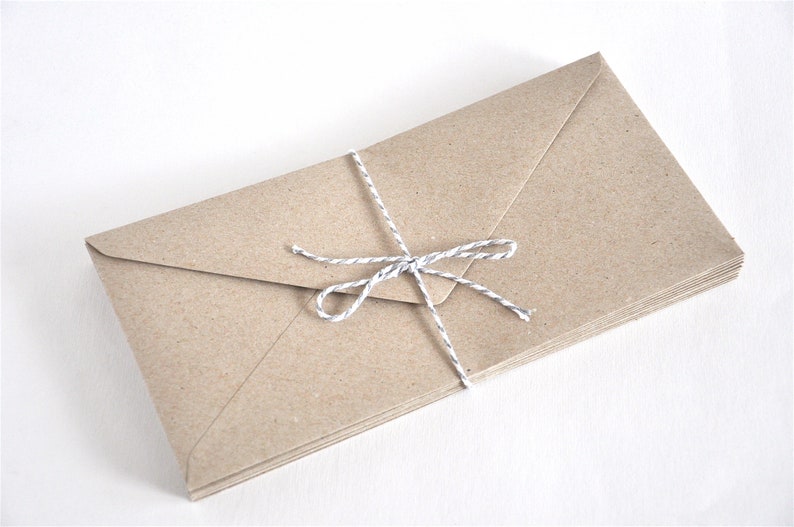 May include: A stack of brown paper envelopes tied together with a white and gray twine bow.