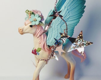 Schleich unicorn cake topper wearing a floral crown and mini flag with wording of your choice. Add extra accessories.