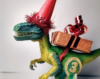 Schleich Dinosaur cake topper, wearing a party hat, add a parcel/Balloon.  Personalized birthday badge.
