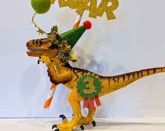 Schleich Dinosaur cake topper, wearing a party hat, add a parcel/Balloon.  Personalized birthday badge.