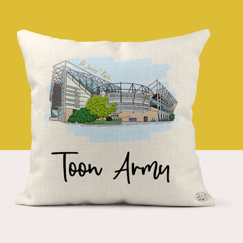 May include: A white pillow with a black and white illustration of St. James' Park, the home of Newcastle United. The text "Toon Army" is printed below the illustration.