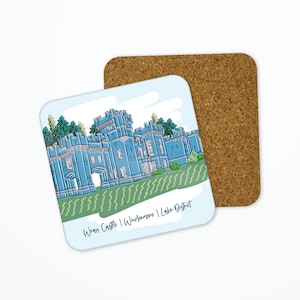 May include: Square coaster featuring a blue illustration of Wray Castle in the Lake District. The coaster has a white background with green and blue accents. A cork coaster is next to it.