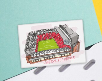 Può includere: Un magnete rettangolare bianco con un'illustrazione di uno stadio di calcio. Lo stadio ha posti a sedere rossi e un campo verde. Il testo "Liverpool FC | ANFIELD" è scritto in rosso. L'illustrazione è delineata in nero.