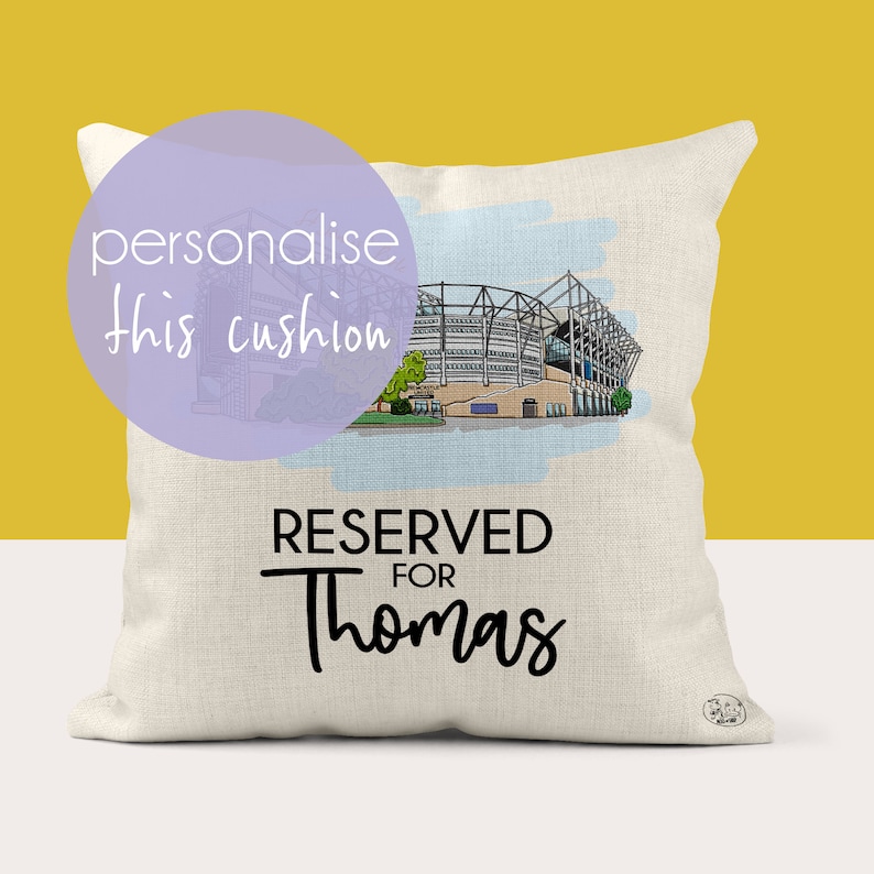 May include: A white cushion with a drawing of a stadium and the text "RESERVED FOR Thomas".