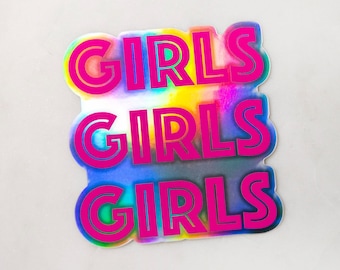 May include: A holographic sticker with the word "GIRLS" stacked three times in a vibrant pink font. The sticker has a colorful, iridescent background with shades of blue, yellow, and green.