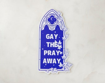 May include: A blue sticker with a gothic arch design and ivy vines. The sticker says "Gay. The. Pray. Away."