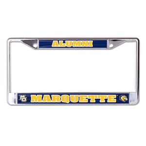 May include: A chrome license plate frame with the word "ALUMNI" in gold letters on a navy blue background at the top. The bottom has "MARQUETTE" in gold letters on a navy blue background.