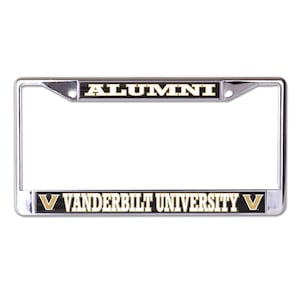 May include: A chrome license plate frame with a black background and gold lettering. The top band says "ALUMNI" and the bottom band says "VANDERBILT UNIVERSITY" with a gold "V" on each side.