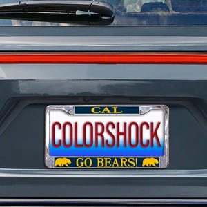 May include: A license plate frame with the word "CAL" at the top. The license plate reads "COLORSHOCK" in red letters over a blue background. The bottom of the plate says "GO BEARS!" with a yellow bear graphic.