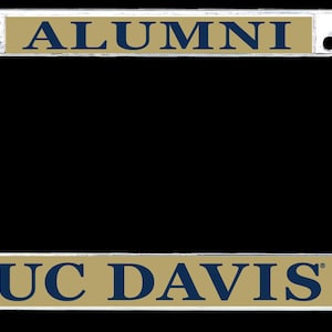 May include: A rectangular chrome license plate frame featuring a gold-colored insert. The top bar displays the word ALUMNI in dark blue lettering. The bottom bar features the text UC DAVIS in dark blue, flanked by two dark blue C-A logos.