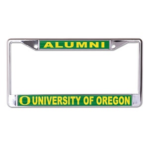 May include: A chrome license plate frame with green and yellow accents. The top bar reads "ALUMNI" and the bottom bar reads "UNIVERSITY OF OREGON".