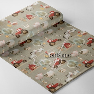 May include: A roll of fabric with a farm animal pattern. The design features red tractors, sheep, cows, chickens, trees, and barns on a light green background. The fabric has the text "NoirBlanc" printed on it.