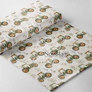 May include: A roll of fabric featuring a repeating pattern of olive green tractors with brown wheels and accents, interspersed with small floral and leaf illustrations. The fabric has a cream-colored background and the text "NoirBlanc" is visible.