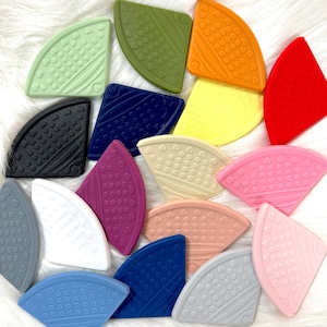 May include: A set of 15 colourful silicone corner guards with different patterns. Each guard is shaped like a quarter circle and has a textured surface.