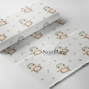 May include: White fabric featuring a repeating pattern of small, light green and brown watercolor turtles interspersed with tiny hearts and starfish. The text NoirBlanc impression textile broderie is printed in black in the center.