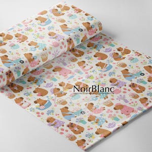 May include: A roll of white fabric featuring a repeating pattern of brown capybaras engaged in gardening activities, including pushing wheelbarrows, watering flowers, and carrying baskets, with the text NoirBlanc impression textile broderie.