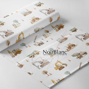 May include: White fabric roll with a repeating pattern of construction vehicles, trees, and traffic cones in shades of brown, yellow, and gray. The fabric has the text "NoirBlanc" printed on it.