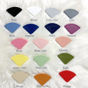 May include: A set of 16 silicone teethers in various colors, including black, white, gray, blue, navy, mauve, rose, rose clair, quartz, yellow, green, khaki, beige, orange, and red. Each teether is shaped like a half-circle with a textured surface.