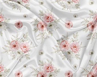 May include: White satin fabric with a repeating pattern of watercolor roses in shades of pink and white, accented by green leaves. The fabric is draped, creating soft folds and shadows.