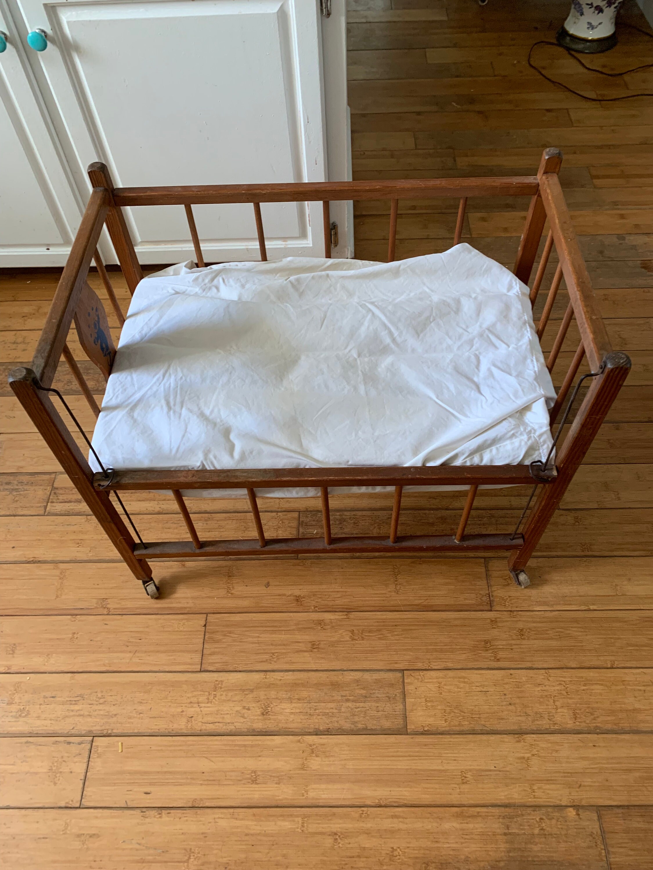 A Fantastic Wooden Doll Crib With Drop Down Side and Clown Picture
