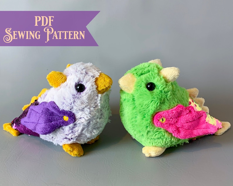 Pode incluir: Dois brinquedos de pel&uacute;cia, um roxo e branco com detalhes amarelos e uma asa roxa, e outro verde com detalhes amarelos e uma asa rosa. Ambos os brinquedos t&ecirc;m a forma de um p&aacute;ssaro com olhos grandes e est&atilde;o sentados em uma superf&iacute;cie cinza. O texto "PDF SEWING PATTERN" &eacute; vis&iacute;vel no canto superior esquerdo da imagem.