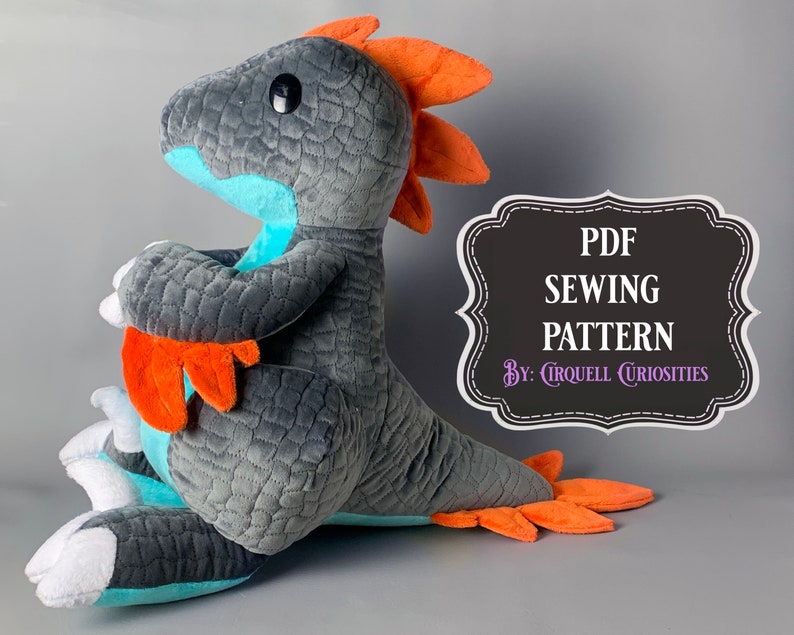 May include: A gray and teal plush dinosaur with orange accents. The dinosaur is sitting on its haunches with its tail curled around its legs. The text "PDF SEWING PATTERN By: Cirquell Curiosities" is on a black sign behind the dinosaur.