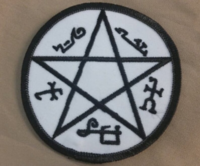 May include: A white, round patch with a black embroidered pentagram and five symbols around it. The symbols are: "Asmodeus", "Lilith", "Belial", "Lucifer", and "Samael".