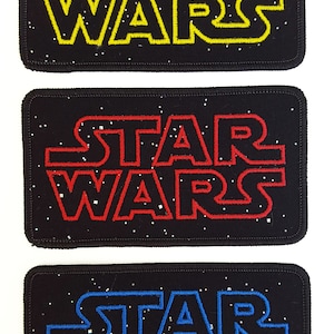May include: Three black fabric patches with white speckles. Each patch features the text "STAR WARS" in a different color: yellow, red, and blue.