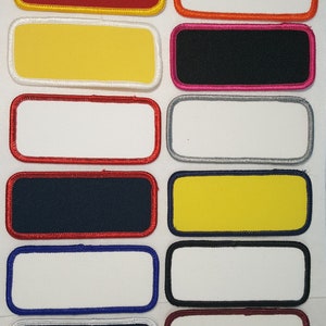 May include: Ten blank rectangular patches with different colored borders. The patches are made of fabric and have a white background. The borders are red, yellow, orange, black, gray, blue, and maroon.