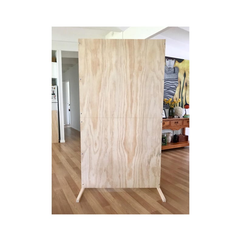 Puede incluir: Un panel de fondo de madera clara independiente con un acabado liso y natural. El panel est&aacute; hecho de madera contrachapada y tiene dos soportes horizontales. El panel est&aacute; de pie sobre un suelo de madera.