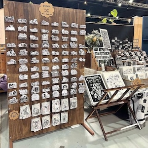 Puede incluir: Un tablero de madera con una variedad de pegatinas en blanco y negro a la venta. Las pegatinas est&aacute;n organizadas en filas y columnas en el tablero. El tablero est&aacute; etiquetado "Sticker Sheet 10 &euro;".