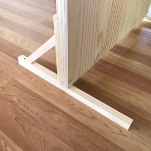 Puede incluir: Un soporte de madera con una estructura de soporte triangular y una base rectangular. El soporte est&aacute; hecho de madera de color claro y tiene un acabado natural.