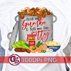 Könnte beinhalten: Weißes T-Shirt mit einer Grafik eines Topfes voller Gumbo, Garnelen und Gemüse. Der Text "feed me Gumbo & tell me I'm pretty" ist in roter Schrift. Enthält ein Logo unten.
