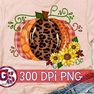 Puede incluir: Camiseta color melocot&oacute;n con un dise&ntilde;o de calabaza grande y colorido. La calabaza tiene secciones de estampado de leopardo, lunares naranjas y cuadros rojos. Los girasoles y las vides verdes acent&uacute;an la calabaza. Tambi&eacute;n se ve el texto "300 DPI PNG".