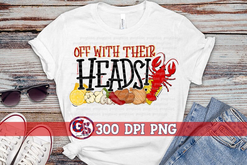 Op de afbeelding: Wit T-shirt met de tekst "Off with their heads!" in zwarte letters. Het ontwerp bevat een rode kreeft, citroenen, uien, knoflook en paprika's.