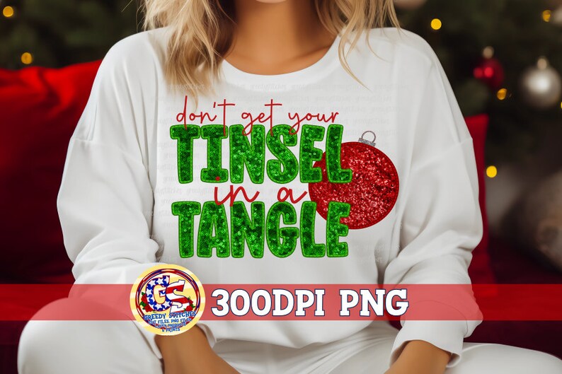May include: White sweatshirt with the text "don't get your TINSEL in a TANGLE" in green and red. A red glittery Christmas ornament graphic is on the right. The bottom of the image has a logo and the text "300DPI PNG".