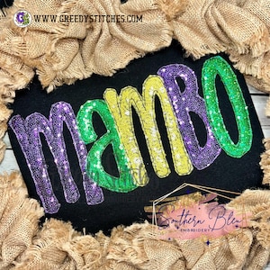 May include: A black fabric with the word "mambo" embroidered in purple, green, and yellow sequins. The word is in a fun, whimsical font.