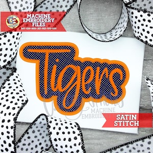 May include: An embroidered design featuring the word "Tigers" in orange script over a navy blue polka-dot background, outlined in orange. The design is surrounded by black and white polka dot ribbon. The text "MACHINE EMBROIDERY FILES" and "SATIN STITCH" are also visible.