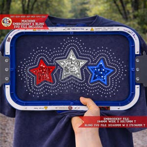 Könnte beinhalten: Ein marineblaues T-Shirt mit einem Maschinenstickdesign aus drei Sternen in Rot, Silber und Blau. Das Shirt wird in einem blauen Stickrahmen gehalten. Der Text auf dem Bild lautet "MACHINE EMBROIDERY & BLING SVG FILE INCLUDED". Die Stickdatei ist 24,4 cm breit x 10,57 cm hoch.