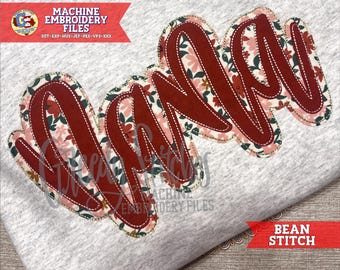May include: A grey t-shirt featuring the word "Nana" embroidered in a cursive style. The letters are a deep red with a floral pattern and white stitching. The image also includes text that says "Machine Embroidery Files" and "Bean Stitch".