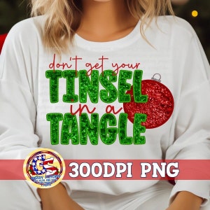 May include: White long-sleeve shirt with the text "don't get your TINSEL in a TANGLE" in green sequined letters. A red glitter ornament graphic is to the right of the text. A logo and the text "300DPI PNG" are at the bottom.